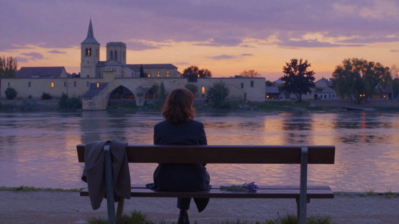 A woman sits alone on a riverside bench at sunset in Avignon, lavender beside her, palace faintly visible.